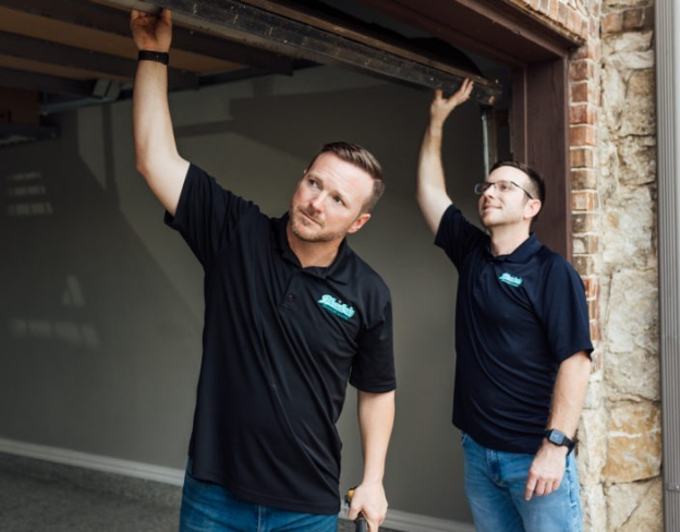 Aaron and Jason Meadows inspecting a garage door