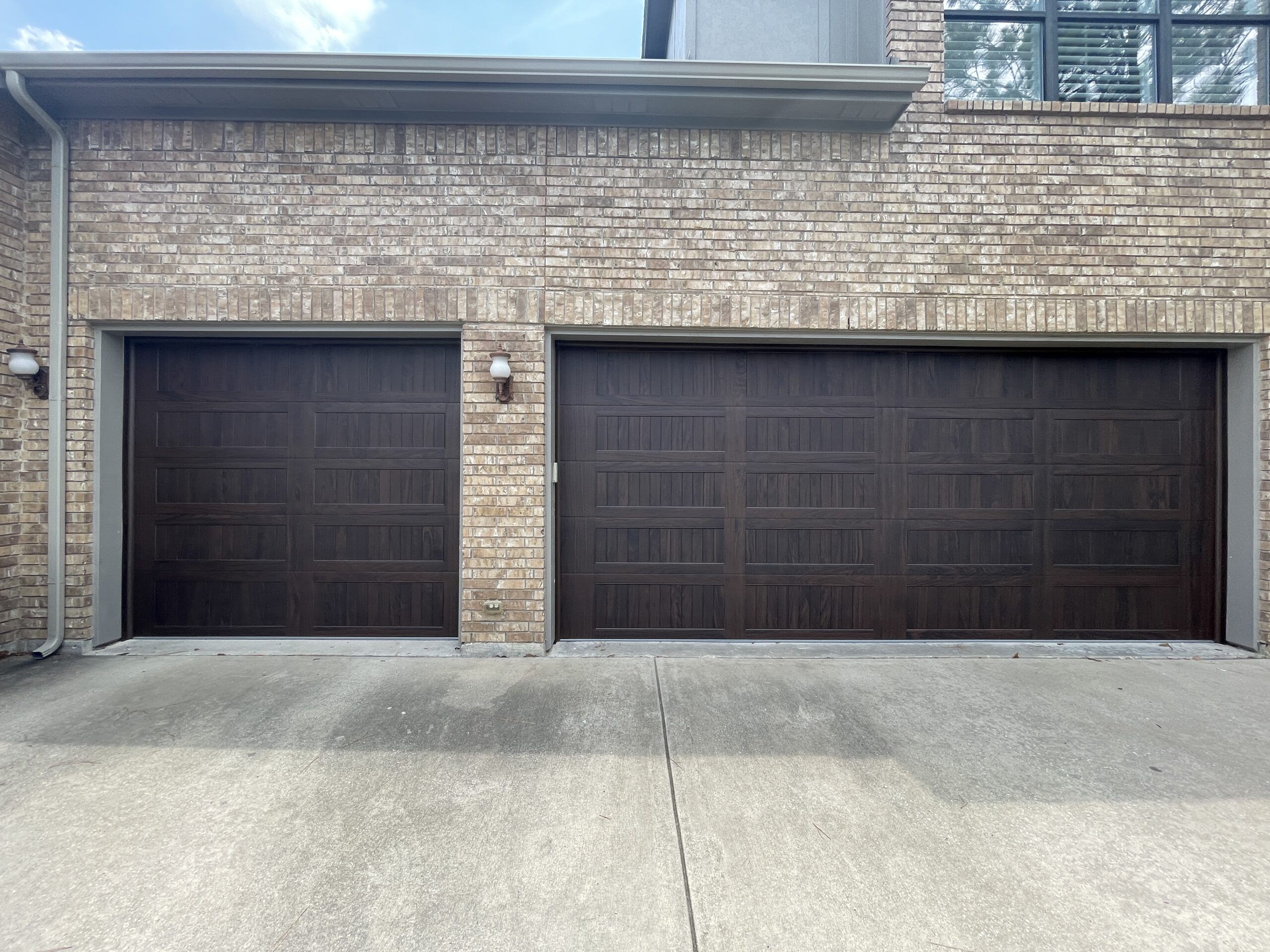 Three car, residential, dark woodtone garage door.